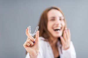 a woman holds a clear aligner