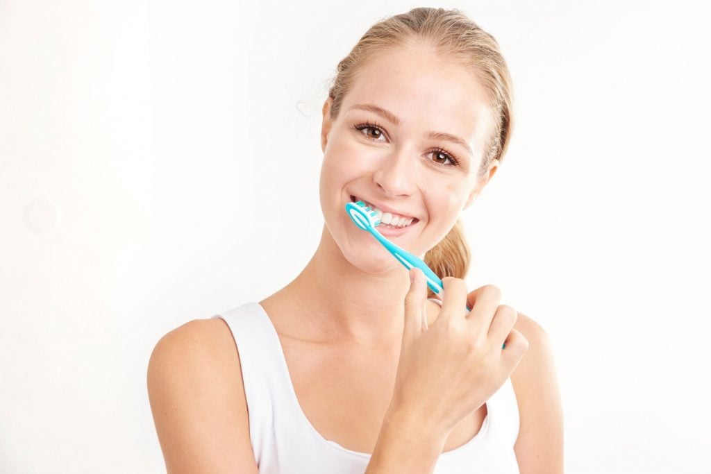 a blonde woman brushing her teeth