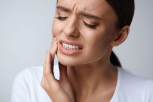 a woman holds her face due to tooth pain