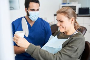 a dental patient smiles into a mirror